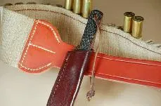 Skinning knife with lanyard secured around a belt tang